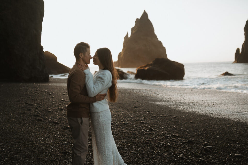 Elopement couple standing face to face and being romantic against the backdrop of Reynisfjara's sunrise