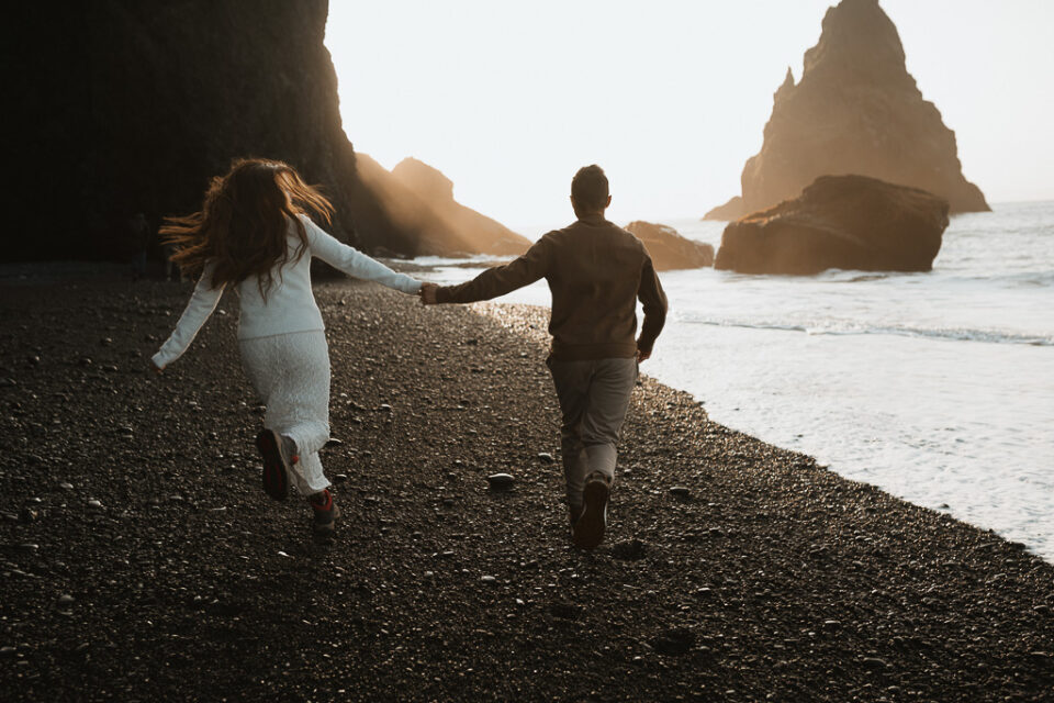 Mesmerizing view of the couple running together on Reynisfjara's volcanic shores, the soft light of sunrise adding a touch of romance to the moment