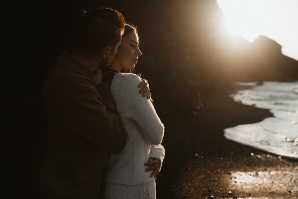 Romantic moment captured as newlyweds embrace and share laughter against the backdrop of Reynisfjara's sunrise
