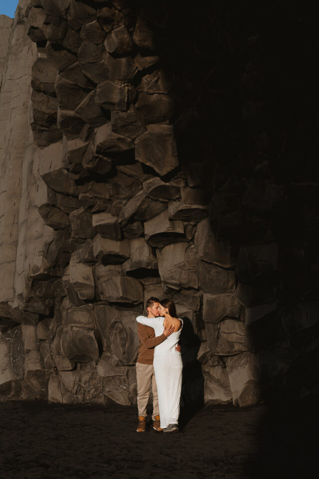 Romantic elopement couple standing amidst the striking basalt columns of Reynisfjara beach, Iceland