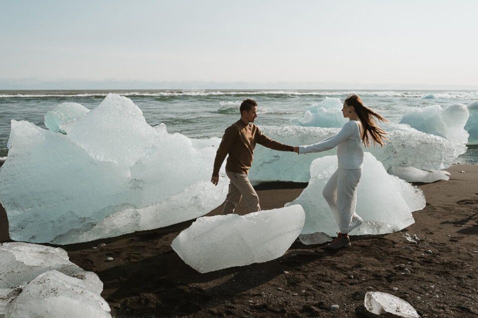 Captivating image of the couple walking along Diamond Beach's shoreline, the icy jewels reflecting the warmth of their love