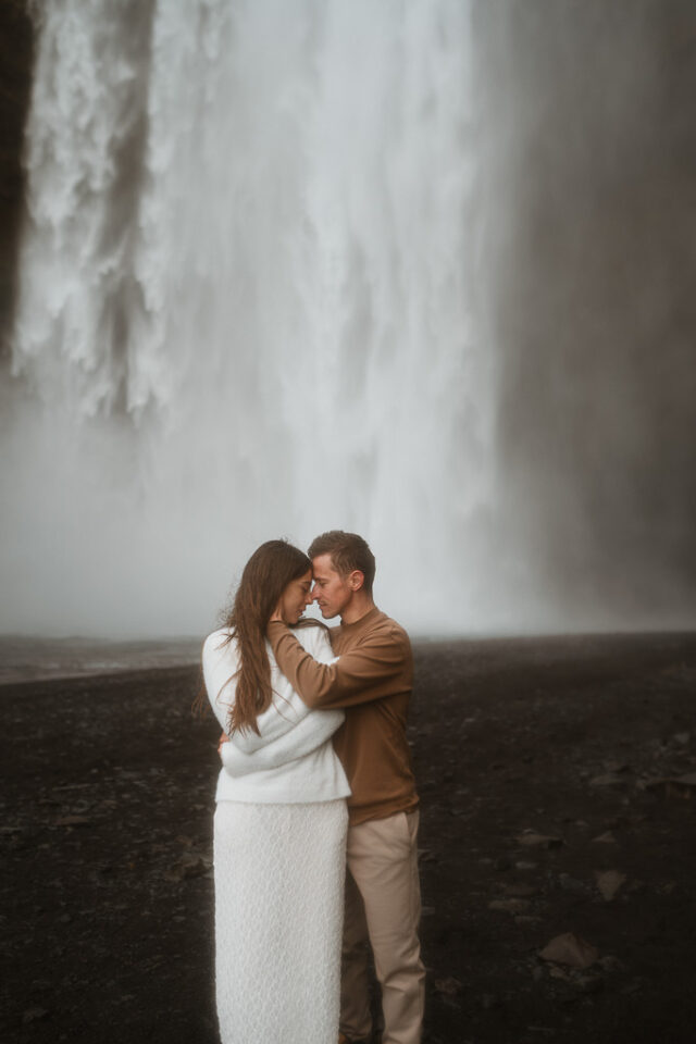 Lovebirds embrace against the majestic Skogafoss waterfall