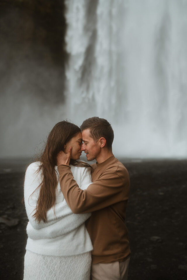Elopement couple sharing a kiss in front of majestic Skogafoss waterfall, Iceland