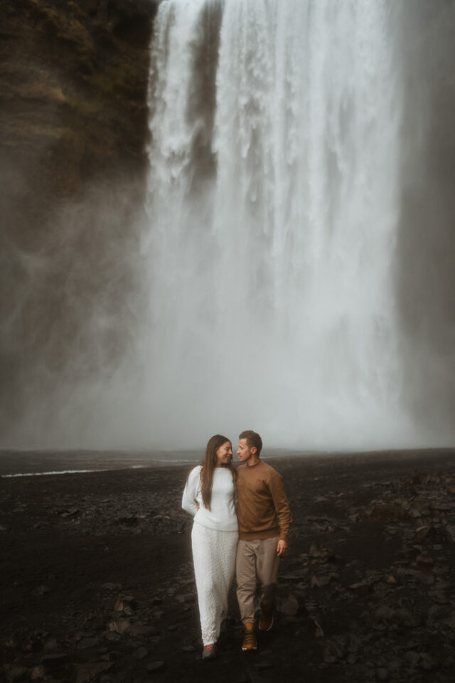 couple holding each other with amazing Skogafoss as backdrop