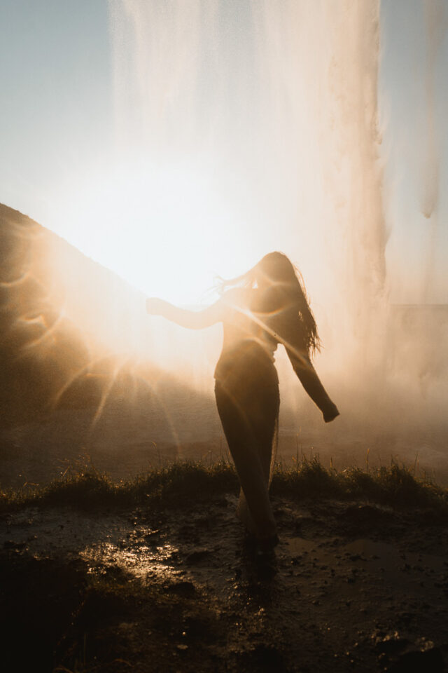 Whimsical moment as the bride dance in the soft light of the sunset, framed by the majestic silhouette of Seljalandsfoss