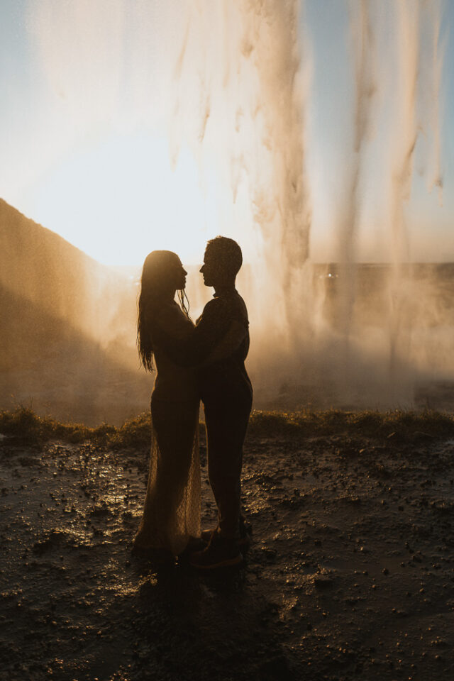 Romantic silhouette of a couple framed against the glowing sunset at Seljalandsfoss