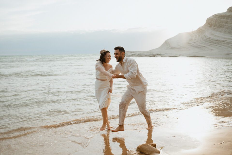 Playful couple moment by the sea in Sicily
