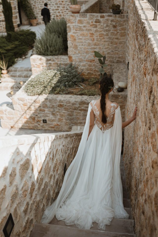 Elegant bride walking through stone courtyard at Alistos Hotel