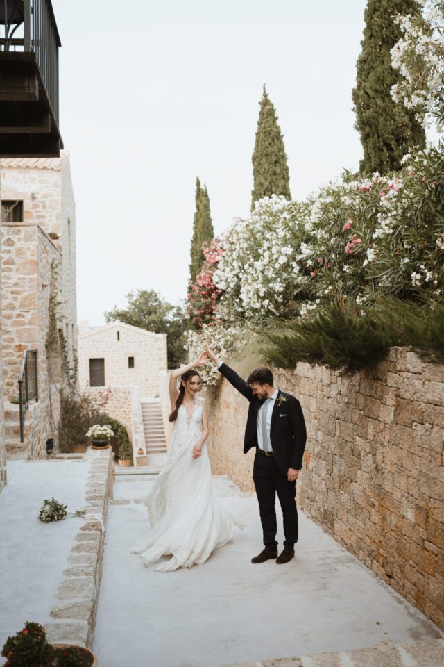 Bride and groom walking through rustic courtyard in Greece